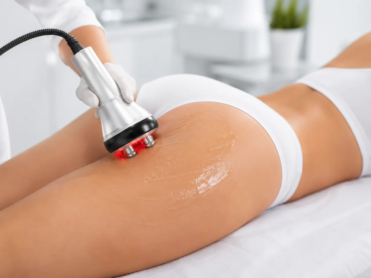 Cellulite reduction device with red light applied to a patient's thigh at the Gold Coast clinic