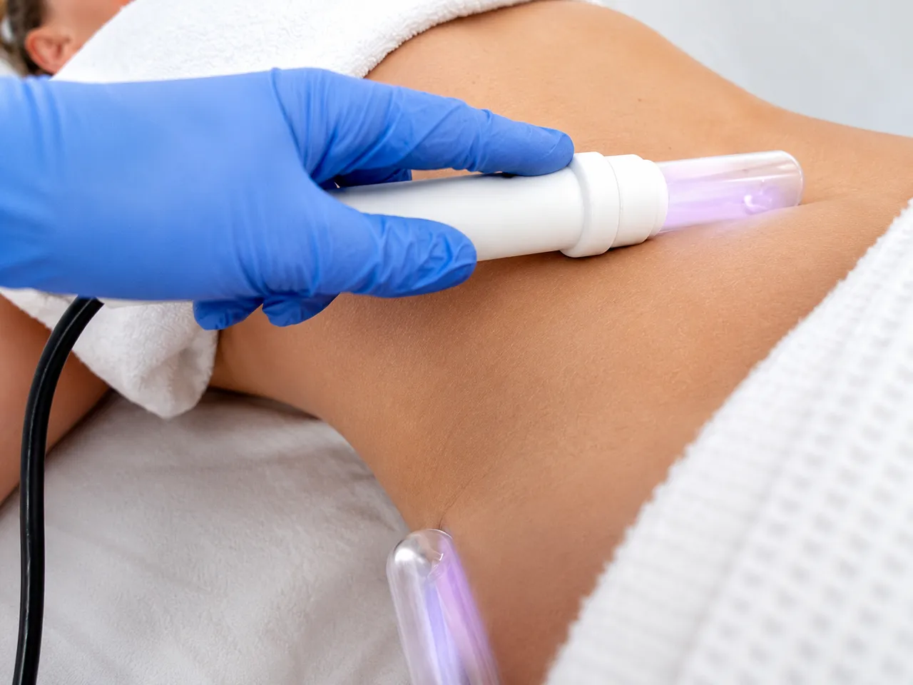 Handheld lymphatic enhancement wands applied to a patient's back at the Gold Coast clinic