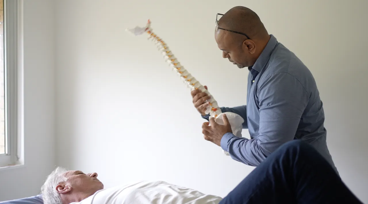Osteopath explaining spinal anatomy with a model spine at the Gold Coast clinic