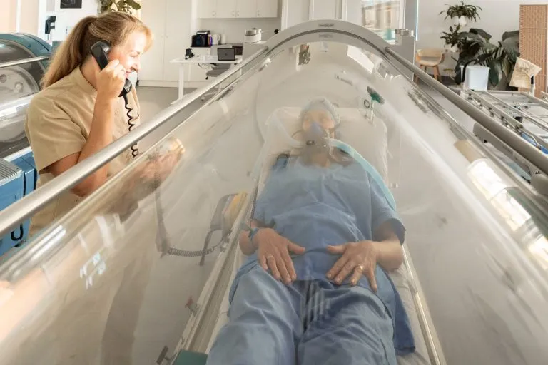 Clinic team member speaking with a patient during a hyperbaric oxygen therapy session