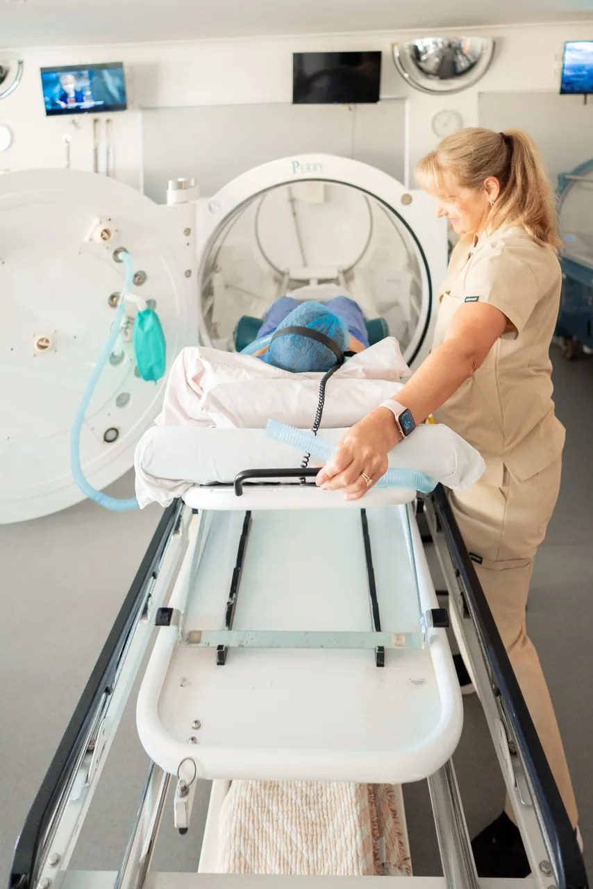 Clinic team member assisting a patient into a hyperbaric oxygen chamber