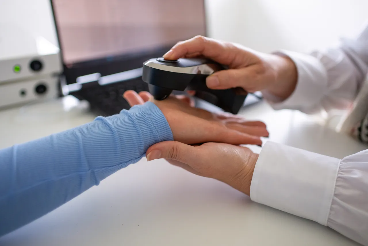 Practitioner holding a quantum frequency device over a patient's hand at the Gold Coast clinic